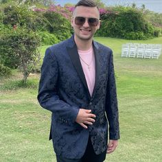 a man in a suit and sunglasses standing on the grass