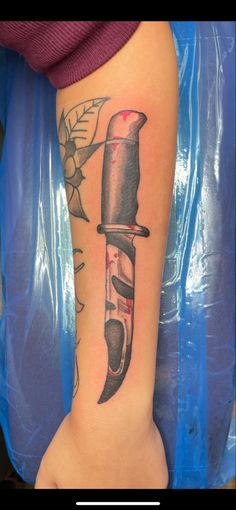 a person with a tattoo on their arm holding a knife