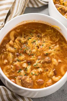 two white bowls filled with pasta and meat soup