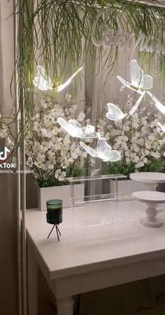 a white table topped with vases filled with flowers next to a wall covered in butterflies