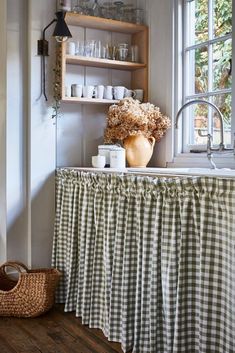 a kitchen with a sink, window and shelf filled with dishes on top of it