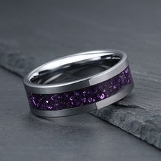 a wedding band with purple glitter inlaying the center on a piece of wood