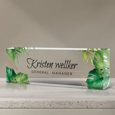 an empty box sitting on top of a counter next to a plant and leaves pattern