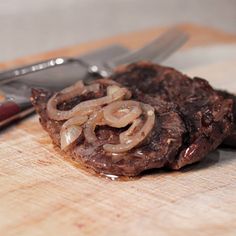 some food is sitting on a cutting board next to a knife and fork with a knife stuck in it