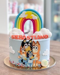 a cake with cartoon characters on it and a rainbow in the background that says sebastano