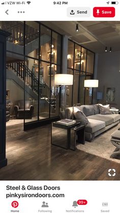 a living room filled with lots of furniture and large glass windows next to a stair case