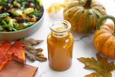 a glass jar filled with liquid sitting on top of a table next to fall leaves