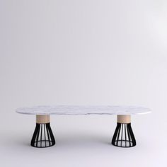 a white table with two black legs and an oval marble top, against a plain background