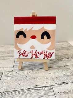 a small wooden easel with a santa face painted on it