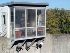 an old outhouse on the side of a concrete wall with metal pipes running through it