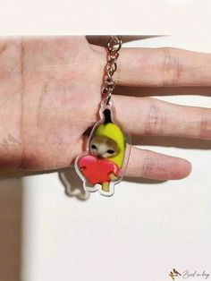 a hand holding a keychain with a small doll in it