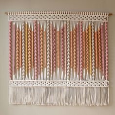 a wall hanging made out of different colored strips of yarn and thread on a white wall