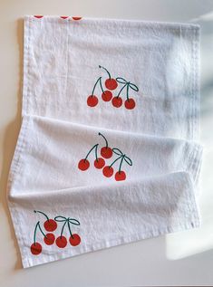 two napkins with cherries on them sitting next to each other