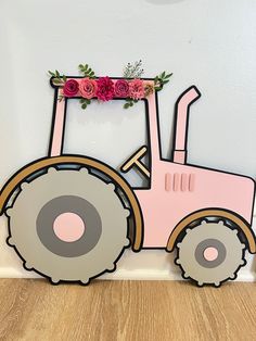 a pink tractor with flowers on the top is sitting in front of a white wall