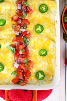 an enchilada with peppers, onions and green peppers on top in a white casserole dish