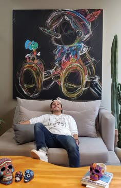 a man laying on top of a couch in front of a painting