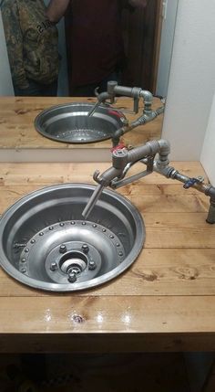 a sink that is sitting on top of a wooden table with pipes coming out of it