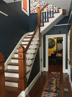 the stairs in this house are painted blue and white with wooden handrails that lead up to the second floor