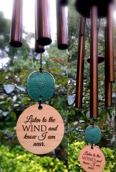 wind chimes hanging from the ceiling in front of some trees and bushes with words written on them