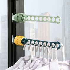 there is a coat rack with clothes hanging on it in front of a window and cityscape