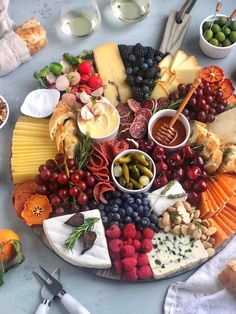 a platter filled with cheeses, fruits and crackers on top of a table