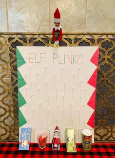 an elf sitting on top of a sign with pins in the shape of a christmas tree