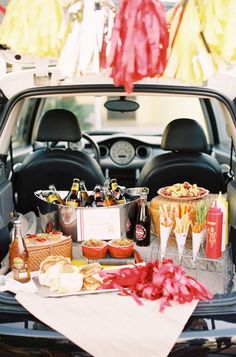 a trunk filled with food and drinks in the back of a car at an event