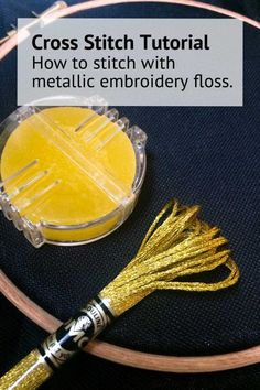 a cross stitch kit with metallic embroidery floss and a yellow tassel on it