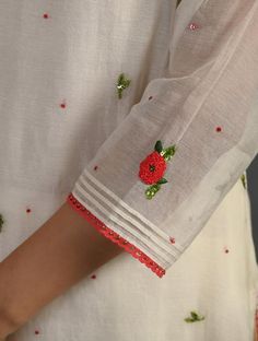 a close up of a person wearing a white shirt with red flowers and sequins