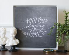 a chalkboard with writing on it next to two busturines and a potted plant