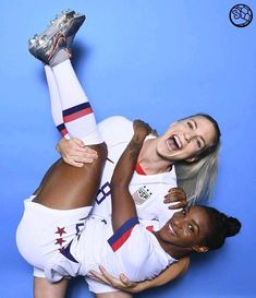 two women in white uniforms are posing for a photo with one holding the other's leg