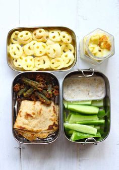 an assortment of food in metal containers on a white table