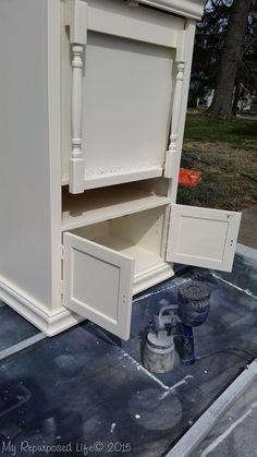 a white cabinet is being painted on the ground