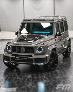 a grey mercedes g - class is parked in a showroom