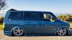 a blue van parked in a parking lot next to the ocean