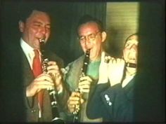 three men in suits and ties are playing the flute together while another man looks on