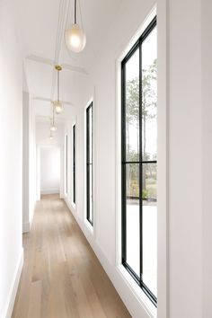 an empty hallway with large windows and wooden flooring is seen in this image from the side