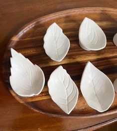 four white leaves are on a wooden tray