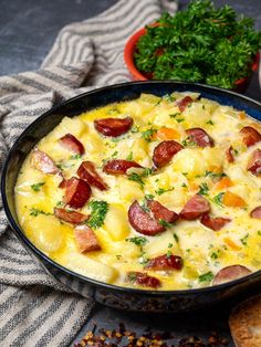 a pan filled with food next to bread and parsley on a tablecloth,