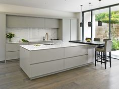 a modern kitchen with an island countertop and bar stools in front of glass doors