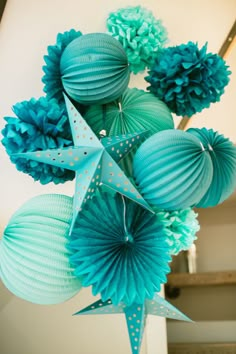 some blue paper balls are hanging from the ceiling with stars and pom - poms