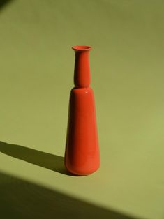 an orange vase sitting on top of a table