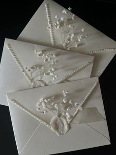 three envelopes with pearls and flowers on them