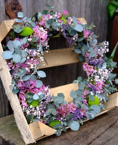 the letter e is made out of wood and has purple flowers on it, along with greenery