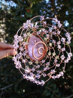 a hand holding a wire and glass object