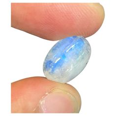 two blue and white marbles sitting on top of each other's fingernails