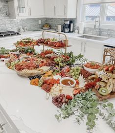 a table filled with lots of food on top of a white counter