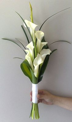 a person holding a bouquet of white flowers in their left hand, with green stems