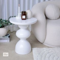 a white table sitting on top of a floor next to a chair and potted plant