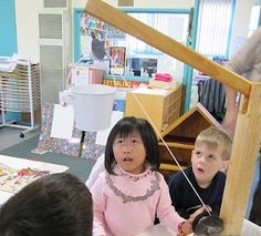 three children are sitting at a table in a classroom